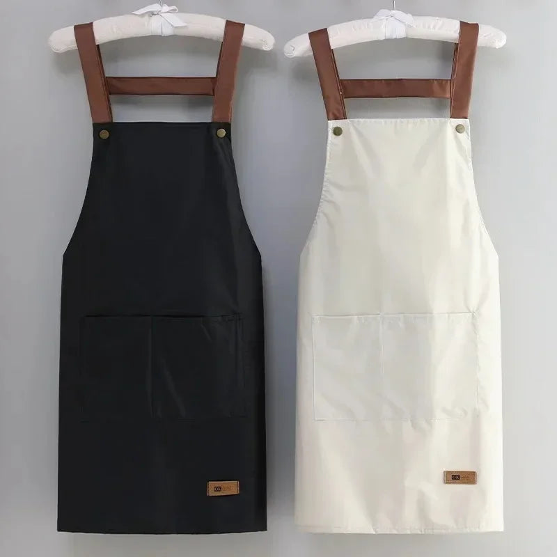 Black and white aprons with brown straps and pockets on a gray background